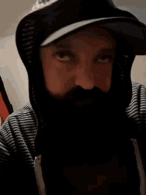 a man with a beard is wearing a hat and a striped jacket .