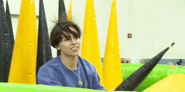 a young man in a blue sweater is sitting on a green and yellow inflatable raft .