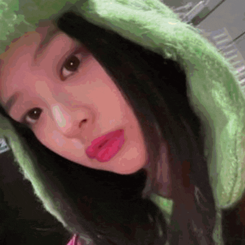 a close up of a woman wearing a green hat and pink lipstick .
