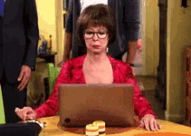 an elderly woman is sitting at a table using a laptop computer .