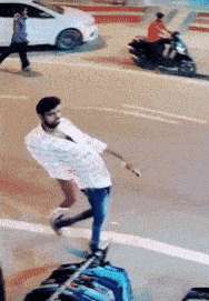 a man in a striped shirt is walking down a street