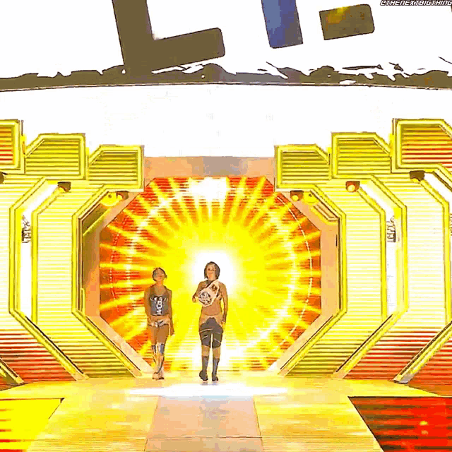 two women are walking through a tunnel with the word l on the wall