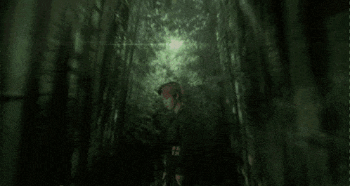 a man is holding a knife in a dark forest