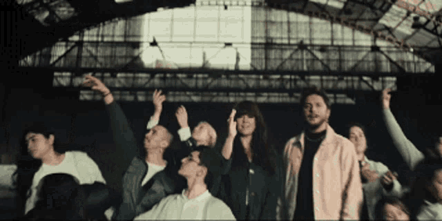 a group of people are standing in a room with their arms in the air