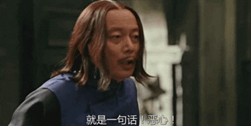 a man with long hair is talking in a foreign language while standing in front of a door .