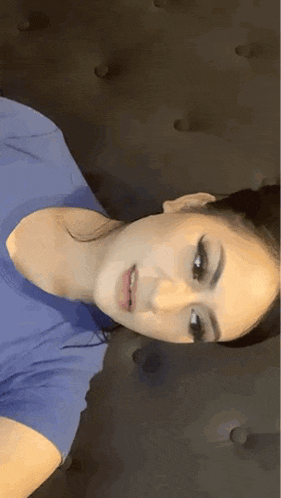 a woman in a blue shirt is laying on a couch .