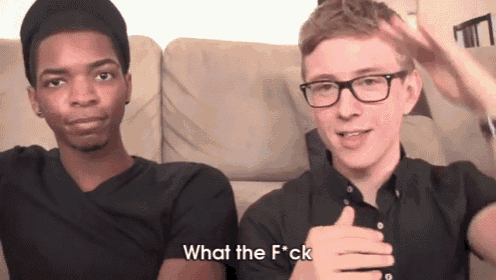 two young men are sitting on a couch and one of them is saying what the f * ck