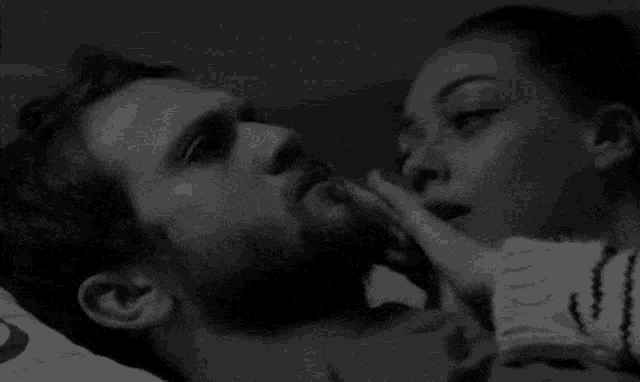 a woman is touching a man 's face in a bed .