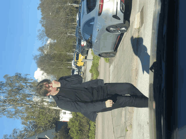 a man standing on a sidewalk next to a parked car