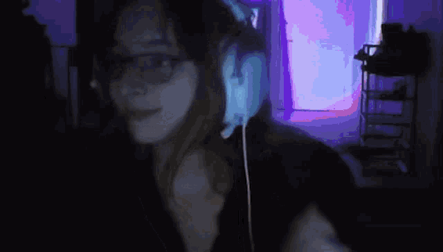 a woman wearing headphones is dancing in a dark room .
