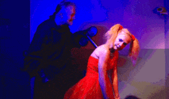 a woman in a red dress is standing in front of a man holding a camera