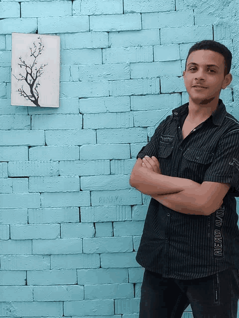 a young man stands in front of a brick wall with his arms crossed wearing a shirt that says always