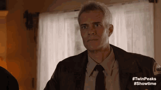 a man in a suit and tie is standing in front of a window in a room .