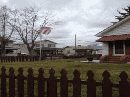 an american flag flies in front of a house with a red awning