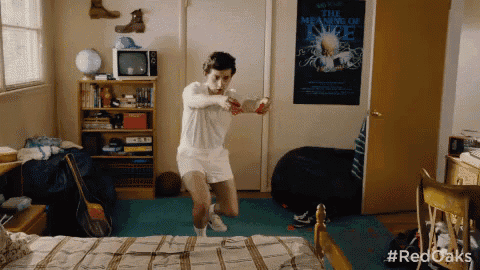 a man in a bedroom with a poster on the wall that says the meaning of love