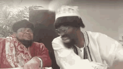 two men are sitting at a table laughing and talking .