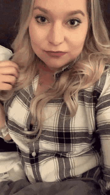 a woman wearing a plaid shirt is sitting on a couch