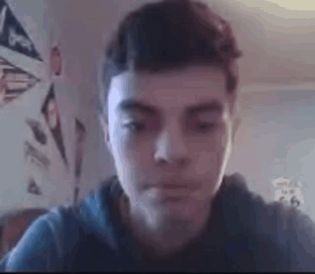 a young man is looking at the camera while sitting in a room .
