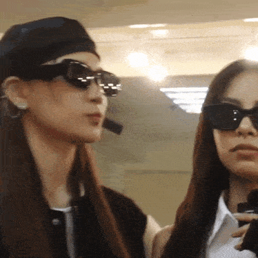two women wearing sunglasses and a black hat