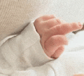 a close up of a baby 's hand with a white sleeve .