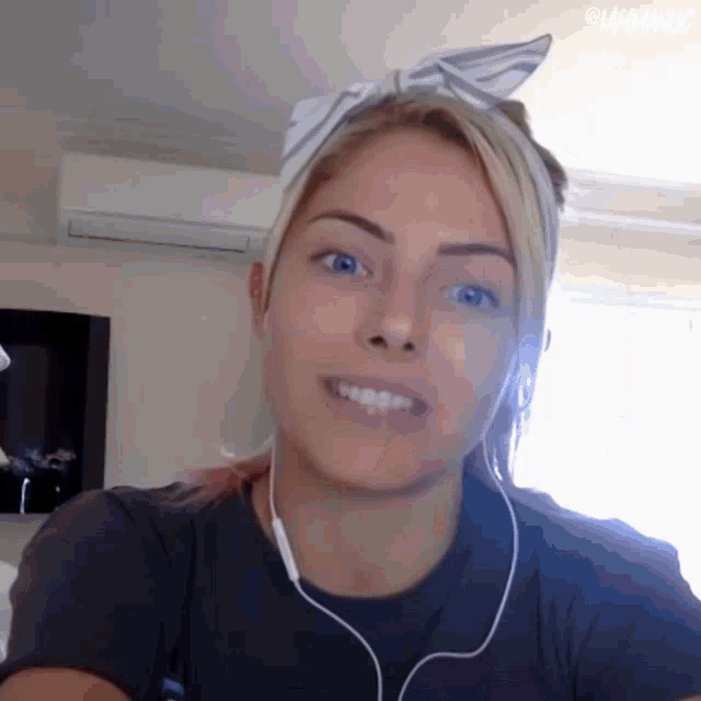 a woman wearing headphones and a headband is smiling for the camera