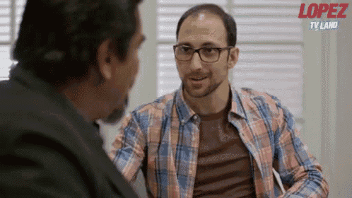 a man in a plaid shirt is talking to another man with the words lopez tv land behind him