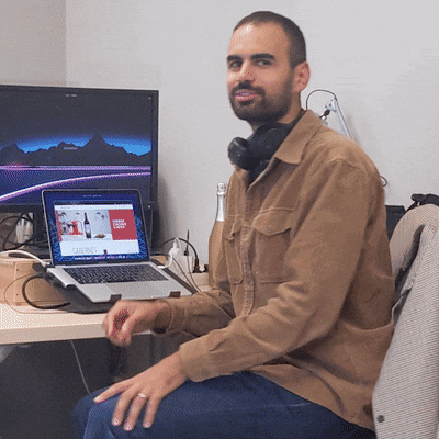 a man sits at a desk with a laptop and a monitor that says ' coca cola ' on it