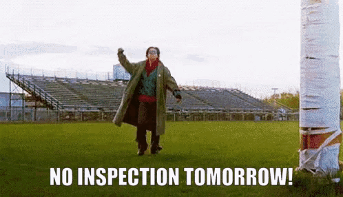a man in a trench coat is walking on a field with the words no inspection tomorrow written on the ground .
