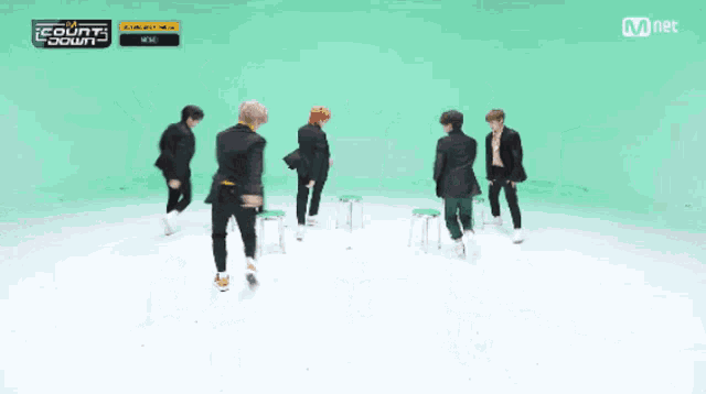a group of young men are dancing in front of a green background with mnet written on it