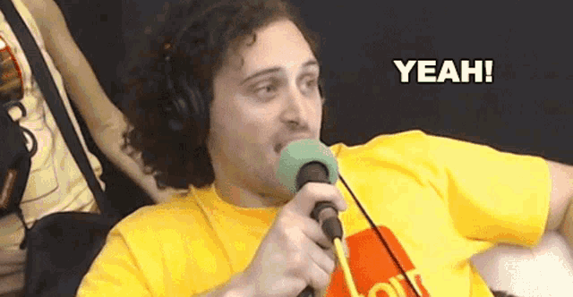 a man wearing headphones and a yellow shirt is holding a microphone and the word yeah is above him