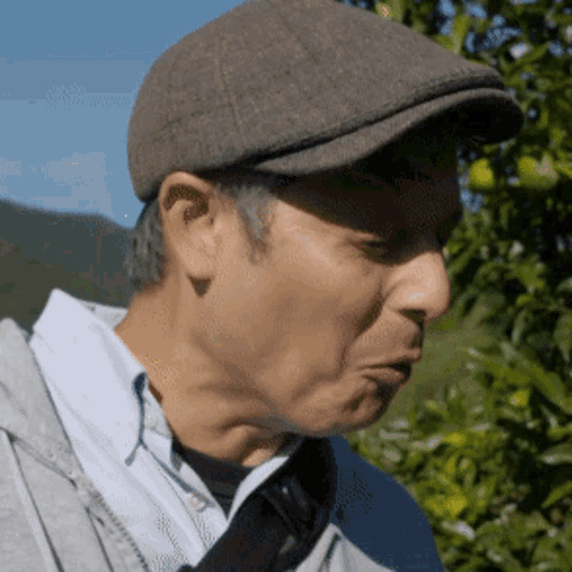 a man wearing a hat and a hoodie looks down