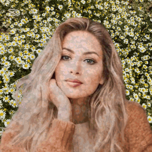 a woman is standing in a field of daisies with her hand on her chin