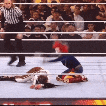 a female wrestler is laying on the ground in a wrestling ring