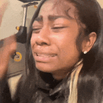 a close up of a woman crying with her eyes closed while sitting in a chair .