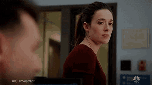 a woman in a red sweater is looking at a man in a room with #chicagopd written on the bottom