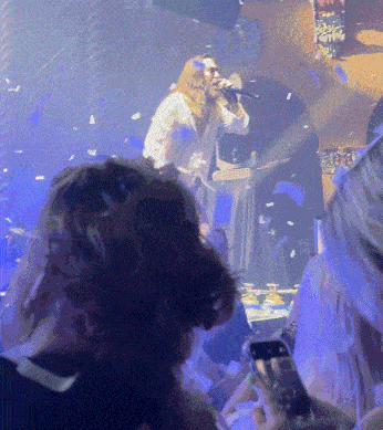 a man singing into a microphone while a crowd watches