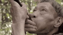 a close up of a man playing a flute in a forest .