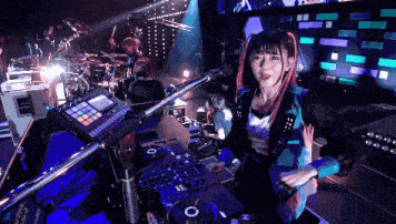 a woman is playing a dj set with a microphone and a drum set behind her