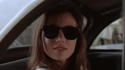 a woman is wearing sunglasses while sitting in a car .