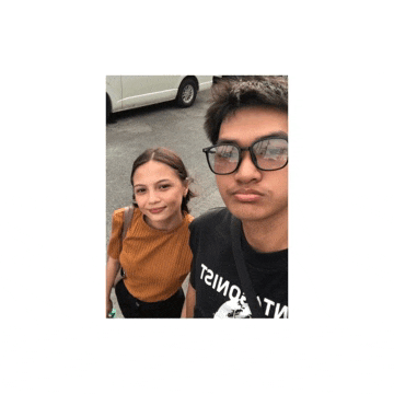 a man wearing glasses stands next to a woman wearing a t-shirt that says t2ioe