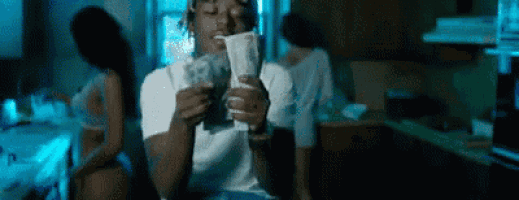 a man in a white shirt is holding a bunch of money in his hand .