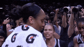 a woman wearing a gatorade shirt stands in a crowd
