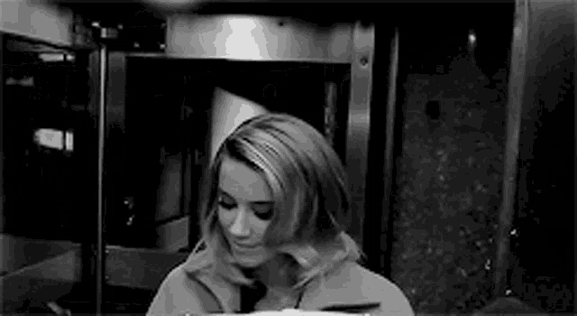 a black and white photo of a woman standing in front of a door .