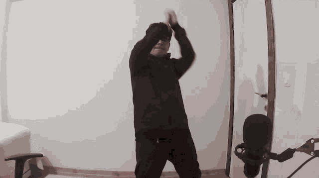a man in a black jacket is dancing in a room