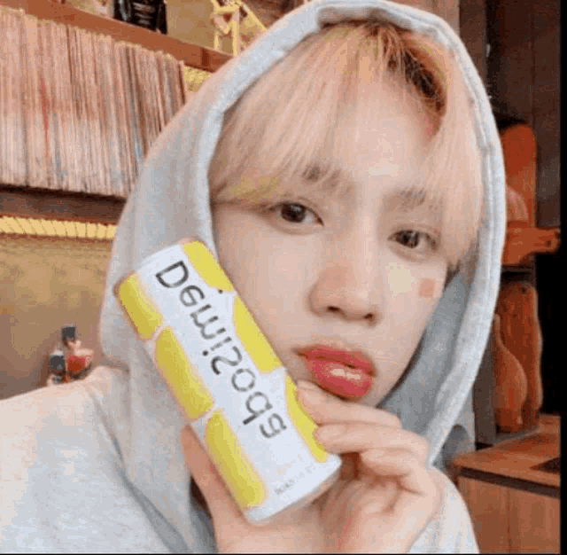 a young man wearing a hoodie is holding a can of soda in his hand .