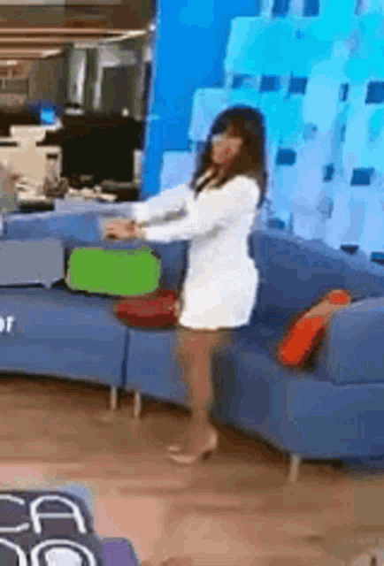 a woman in a white dress is standing on a couch .