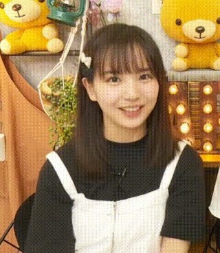 a young girl is smiling in front of a teddy bear .