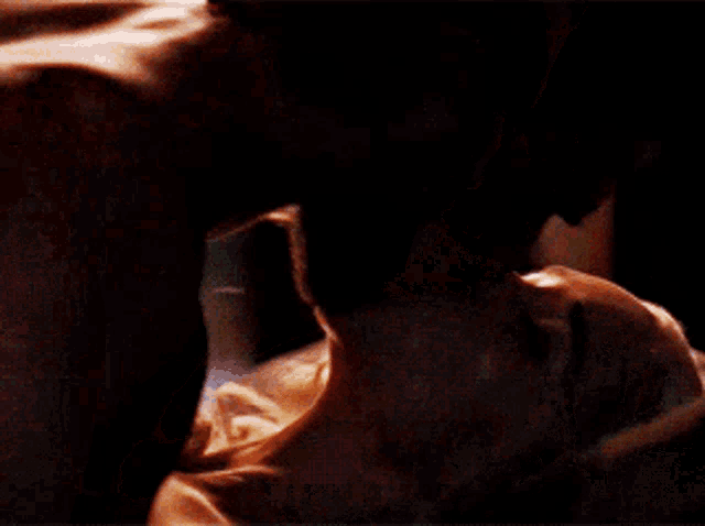 a man is kissing a woman on the neck in a dark room .