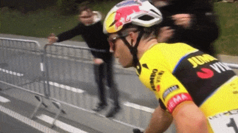 a man wearing a red bull helmet is riding a bike down a road