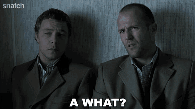 two men in suits are sitting next to each other and one of them is asking a what